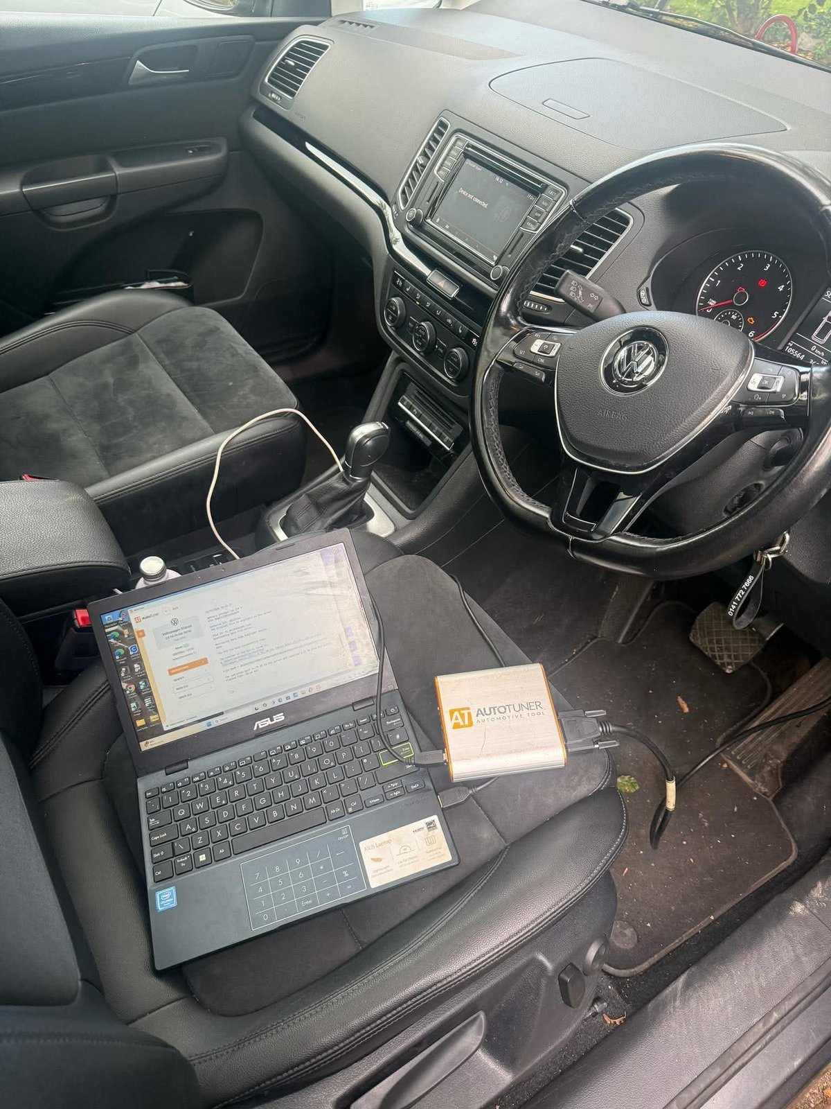 Volkswagen car interior with laptop and work materials on passenger seat, steering wheel and dashboard visible